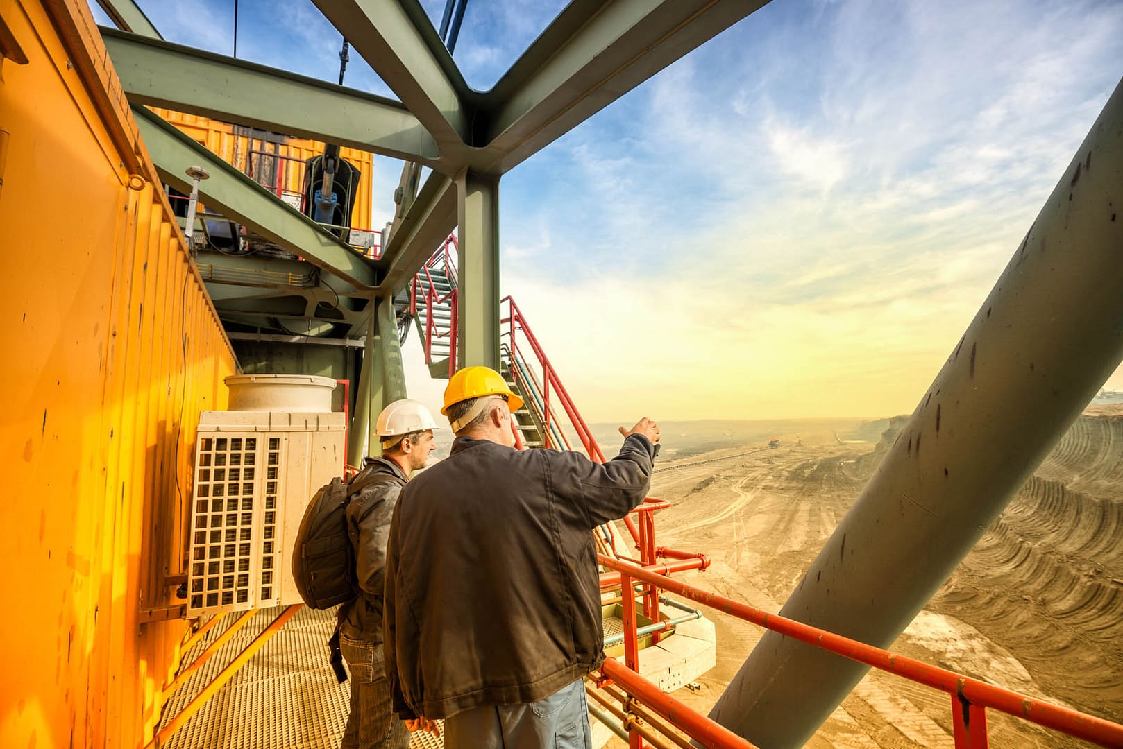 Two coal mine engineers with protective helmets standing on a hu