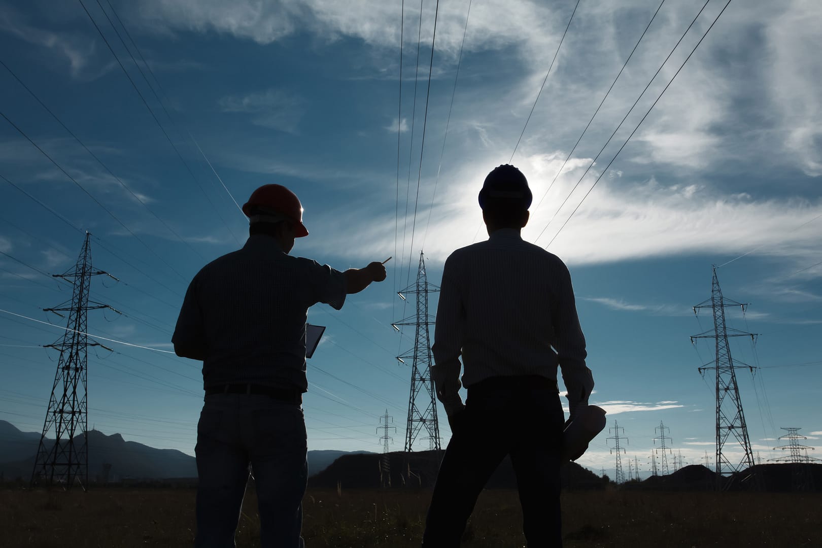 Silhouette of two men at an electricity station
